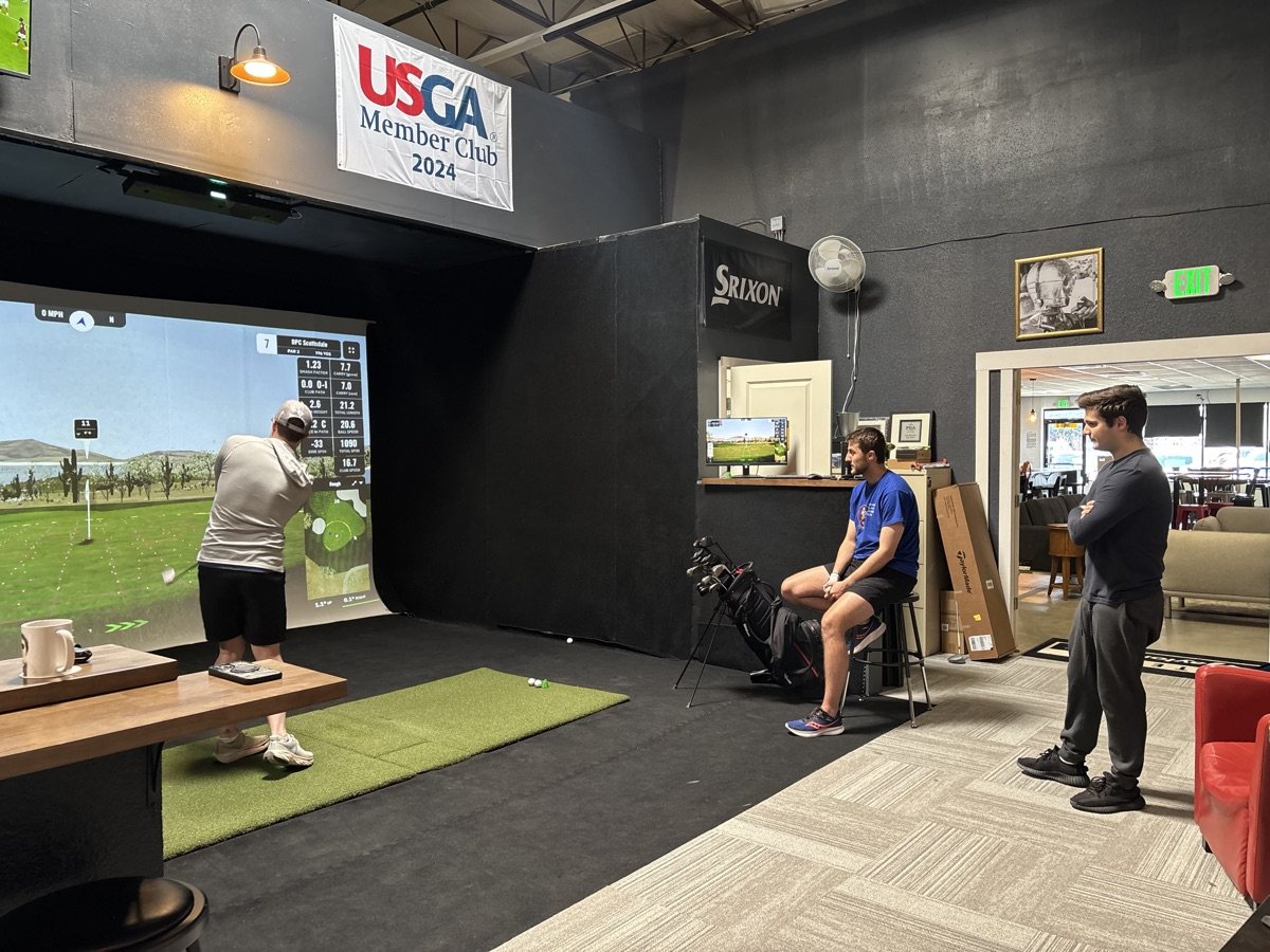 Friends gathered around a COR Golf simulator bay