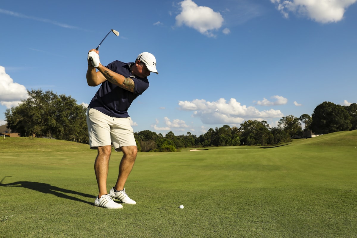 Golfer mid-swing under a blue sky